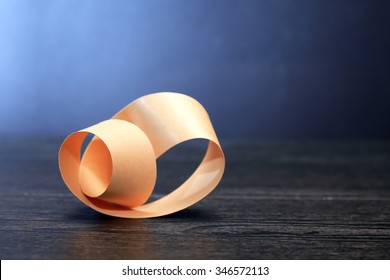 Paper Mobius Strip On Wooden Board Against Dark Background