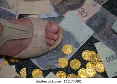 Paper Money And Counterfeit Gold Coins Are On The Ground. Cash Scattered On The Floor. The Woman's Foot Stepping On It. The Crime Scene In A Robbed Bank.