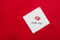 Paper Napkin With Lipstick Mark And Words CALL ME On Red Background, Top View. Space For Text