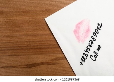 Paper Napkin With Phone Number And Lipstick Mark On Wooden Table, Top View. Space For Text