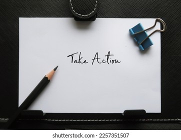 Paper note on black background with handwritten text TAKE ACTION, concept of start really doing the process of doing something in order to deal with a problem or difficult situation, not just planning - Shutterstock ID 2257351507