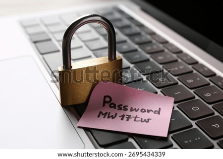 Paper note with password and closed padlock on laptop, closeup