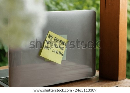 Paper note with text NO POSTING NO LIKING JUST LIVING in laptop garden background. Concept of digital detox, unplugging from technology break. Mindful living
