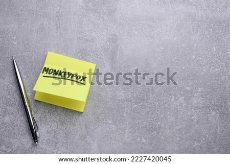 Paper note with word Monkeypox and pen on light grey table, flat lay. Space for text