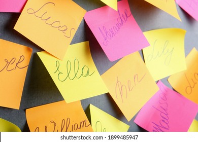 Paper notes with different baby names on grey wall