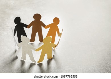 Paper people holding hands on light background. Unity concept