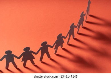 Paper people holding hands on red surface. Community, brotherhood concept. Society and support.