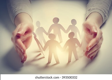 Paper people surrounded by hands in gesture of protection. Concept of insurance, social protection and support.  - Shutterstock ID 393500332