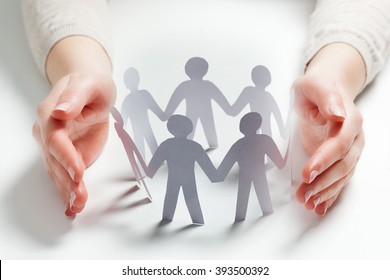 Paper People Surrounded By Hands In Gesture Of Protection. Concept Of Insurance, Social Protection And Support. 