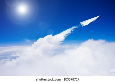 Paper Plane Flying Over Clouds Against Blue Sky