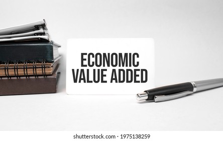 Paper Plate, Glasses, Notepad In Stack,pen And Text Economic Value Added On Business Card