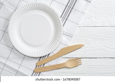 Paper Plate, Wooden Fork And Knife On White Table, Top View. Disposable Tableware