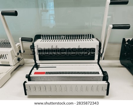 A paper punching and comb binding machine with adjustable punching settings, metal punching pins, and binding mechanism.