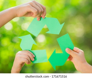 Paper RECYCLE sign in children`s hands against green spring background. Earth day concept - Shutterstock ID 171671516