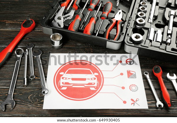 Paper with scheme and box with tools for car repair\
on wooden table