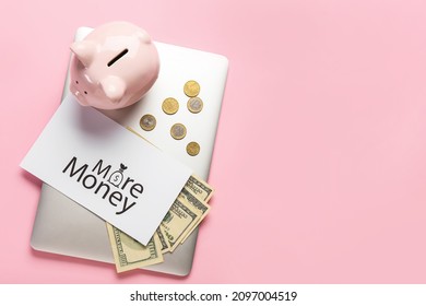 Paper Sheet With Text MORE MONEY, Laptop And Piggy Bank On Color Background. New Year Goals