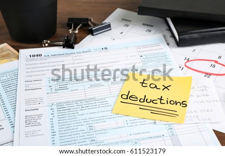 Paper sheet with text TAX DEDUCTIONS and individual tax return form on table