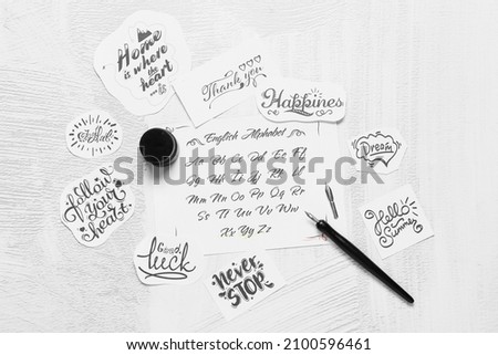 Paper sheets with calligraphic text, nib pen and ink on white background