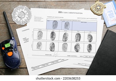 Paper sheets with finger prints, FBI seal, badge with portable radio transmitter on wooden background