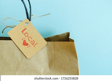 Paper shopping bag with label on blue background. Label with heart and text LOCAL. Shopping concept. Copy space. - Shutterstock ID 1726255828