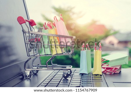 Paper shopping bags in a shopping cart on a laptop keyboard.Easy shopping with finger tips for consumers.Online shopping and delivery service concept.