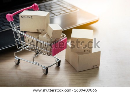 Paper shopping small box express in a shopping cart and laptop notebook on wood table background. Online shopping concept.