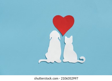 Paper silhouette of a cat, dog and red heart on a blue background. Flat lay, place for text. Veterinary care or animal care.