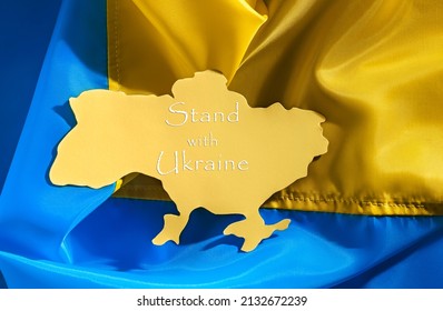 Paper Silhouette Of Ukraine On The Background Of The Ukrainian Yellow And Blue Flag. Stand With Ukraine Concept