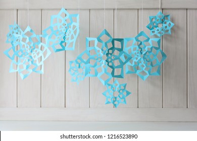 Paper Snowflakes Hanging On White Wooden Background. Christmas Decoration