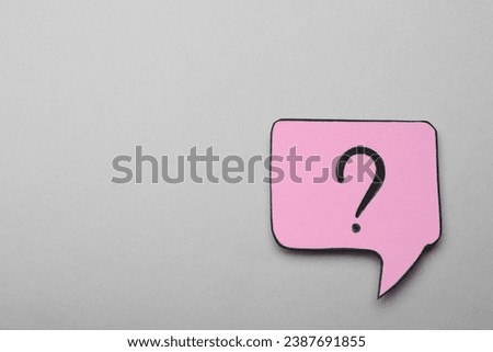 Paper speech bubble with question mark on light grey background, top view. Space for text