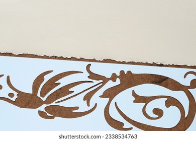 paper stencil with floral flourish or swirl on old art board and beige paper with deckle edge 