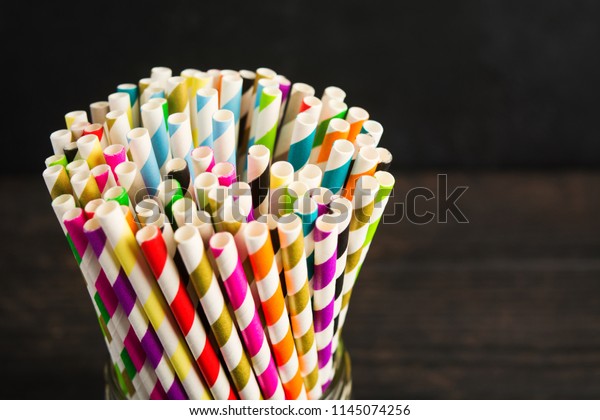 Paper straw of different colors on dark background
with copy space