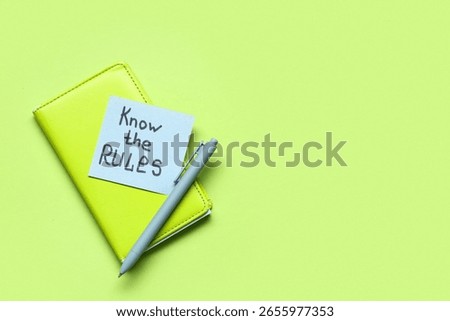 Paper with text KNOW THE RULES and notebook on green background