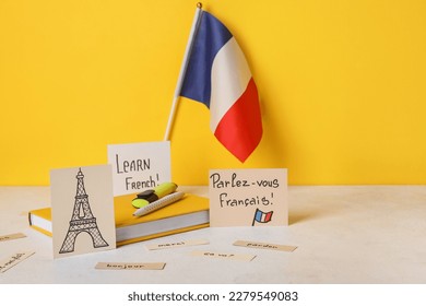 Paper with text LEARN FRENCH, drawn Eiffel Tower, flag and stationery on table near yellow wall - Shutterstock ID 2279549083