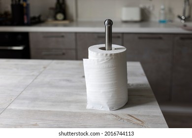 Paper Towel Is In A Holder On A Wooden Table In A Beige Kitchen Interior. Empty Space