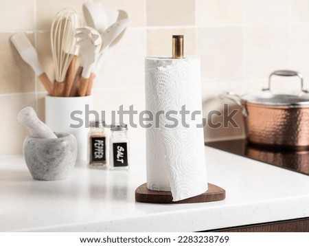 Paper towels on a holder. Stylish bright kitchen and kitchen utensils in the background.