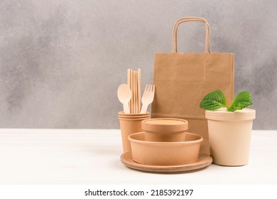 Paper Utensils Bundle - Paper Plates, Food Containers, Bag, Cups And Wooden Cutlery Set Against Gray Wall Background With Copy Space. Sustainable Food Packaging. Eco Tableware 