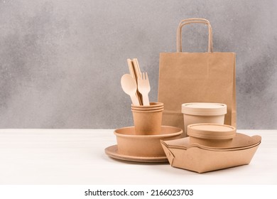 Paper Utensils - Paper Plates, Food Containers, Bag, Cups And Wooden Cutlery Set Against Gray Wall Background With Copy Space. Sustainable Food Packaging Concept. Eco Tableware 