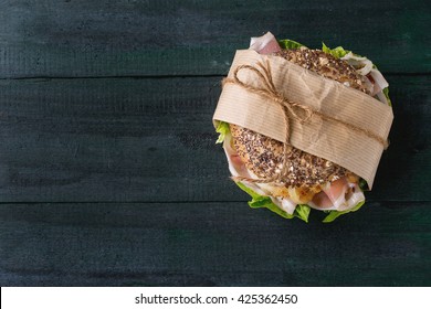 Papered Whole Grain Bagel With Fried Onion, Green Salad And Prosciutto Ham Over Dark Wooden Textured Background. Top View