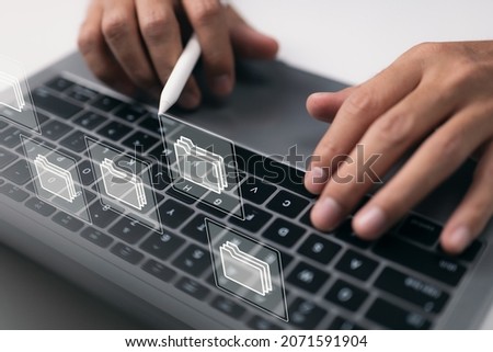 Paperless workplace concept based on e-documents. On a virtual screen, a businessman works on a laptop computer keyboard with electronic document icons.