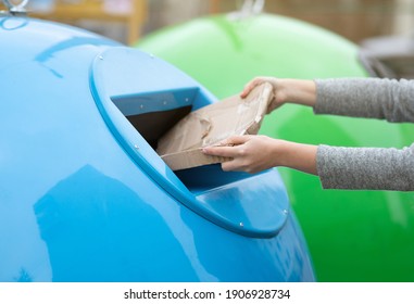 Paperwaste Sorting. Unrecognizable Woman Throwing Carton Package Into Blue Garbage Recycle Bin Outdoors, Eco-friendly Lady Caring About Environment, Cropped Image With Selective Focus