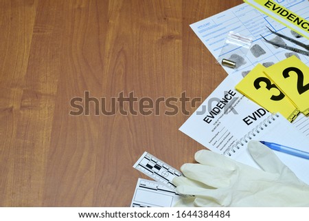 Paperwork during crime scene investigation process in csi laboratory. Evidence labels with fingerprint applicant and rubber gloves on vooden table