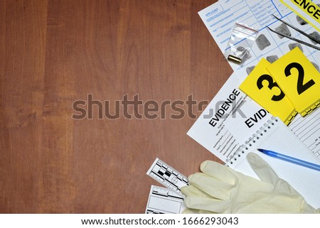 Paperwork during crime scene investigation process in csi laboratory. Evidence labels with fingerprint applicant and rubber gloves on vooden table close up