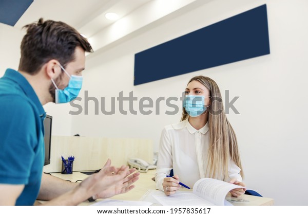 Paperwork for
technical inspection and corona virus. A man and a woman are in a
meeting in the office. The man explains something with his hands as
she looks him straight in the
eye