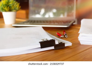 paperworks with black paperclips on top on wooden table in office with office supplies - Shutterstock ID 2158329737