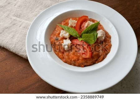 Pappa al Pomodoro, traditional italian tuscan dish, soup with tomatoes and bread. In a white plate. Homemade. Wood background.