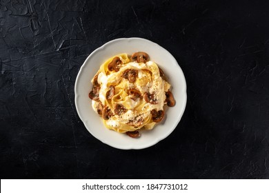 Pappardelle Pasta With Mushrooms, Cream Sauce And Grated Parmesan Cheese, Overhead Shot On A Black Background