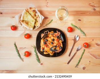 Pappardelle pasta with seafood with tomato sauce, glass of white wine and focaccia bread on wooden table. Top view. - Powered by Shutterstock