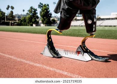 Para athlete with prosthetic legs on sprint starting block. Para athlete man getting ready to run. Para athlete runs with prosthetic legs on a running track. - Powered by Shutterstock