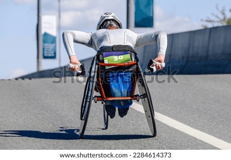 para athlete in wheelchair racing road, movement uphill overpass, marathon race para athletics competition